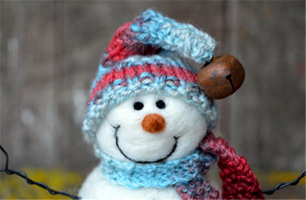 Wool felt handmade creative DIY production of a smiling snowman wearing a hat and scarf