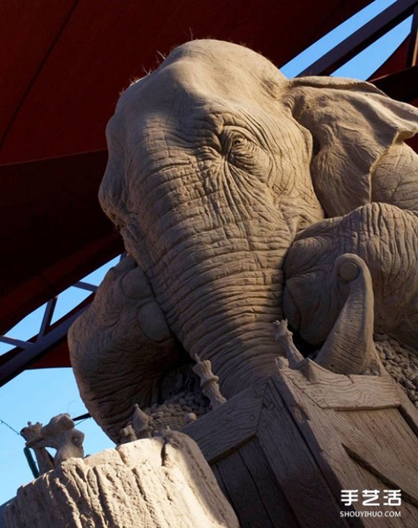 A lifelike sand sculpture in the shape of an elephant and a mouse playing chess, full of a fairy tale atmosphere