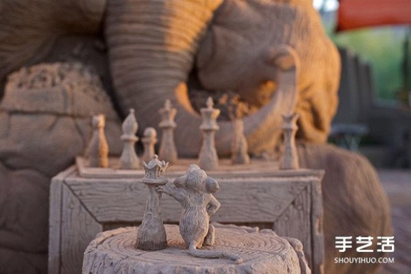 A lifelike sand sculpture in the shape of an elephant and a mouse playing chess, full of a fairy tale atmosphere