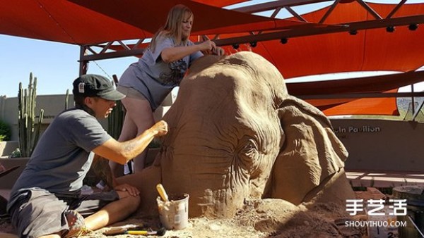 A lifelike sand sculpture in the shape of an elephant and a mouse playing chess, full of a fairy tale atmosphere