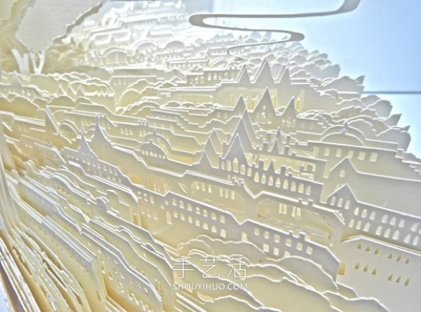 A three-dimensional paper sculpture of a city and forest made from dozens of sheets of paper