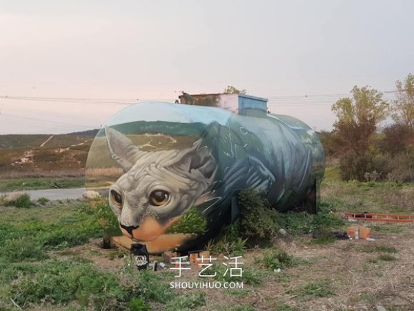 A street artist uses spray paint to transform a petrol tank into a sphinx cat