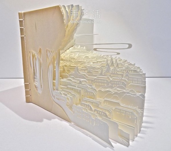 A three-dimensional paper sculpture of a city and forest made from dozens of sheets of paper