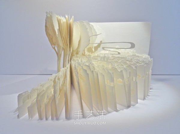 A three-dimensional paper sculpture of a city and forest made from dozens of sheets of paper