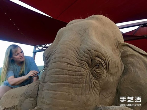 A lifelike sand sculpture in the shape of an elephant and a mouse playing chess, full of a fairy tale atmosphere