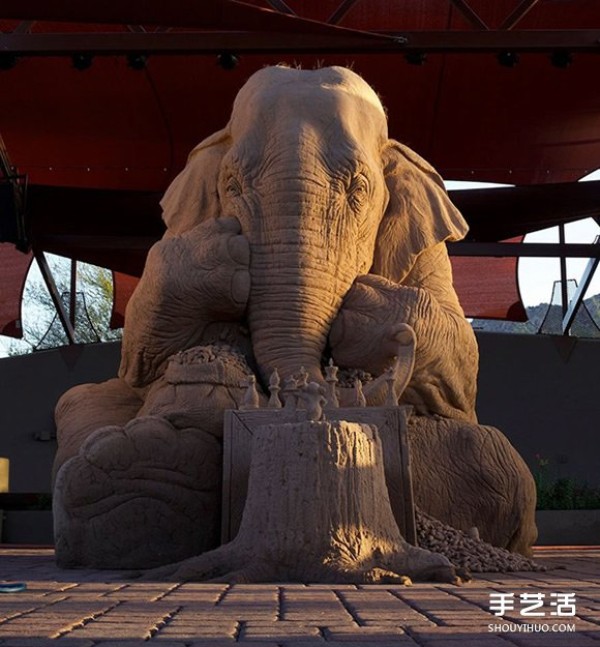 A lifelike sand sculpture in the shape of an elephant and a mouse playing chess, full of a fairy tale atmosphere