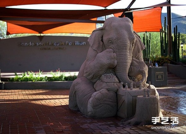 A lifelike sand sculpture in the shape of an elephant and a mouse playing chess, full of a fairy tale atmosphere