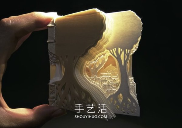 A three-dimensional paper sculpture of a city and forest made from dozens of sheets of paper