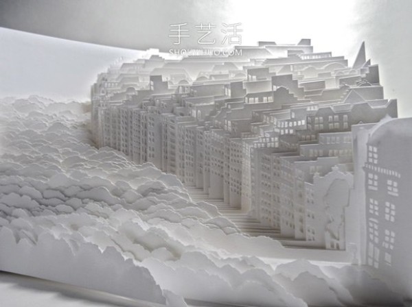 A three-dimensional paper sculpture of a city and forest made from dozens of sheets of paper