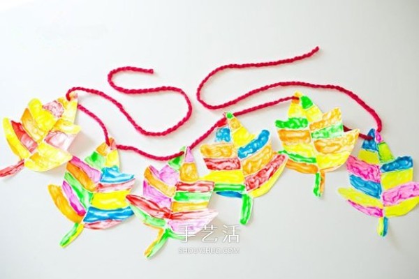 Illustration of how children make handmade New Year hangings with cardboard maple leaves