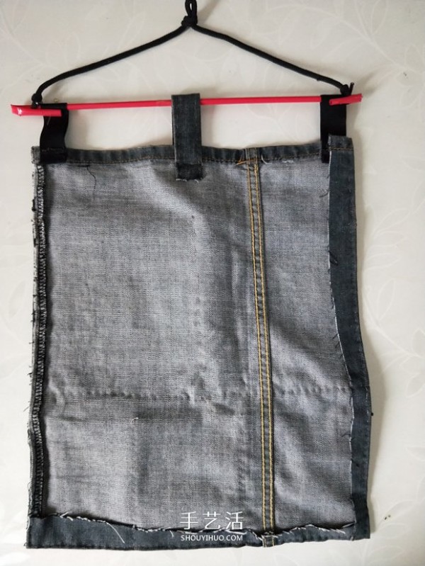 Illustration of a DIY method to make a wall-mounted storage bag from waste jeans