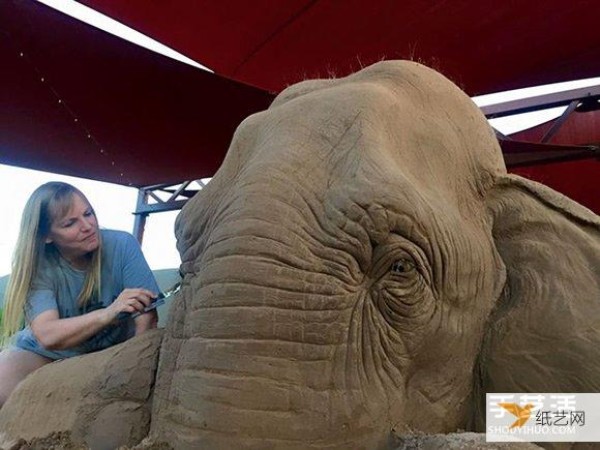 A sand sculpture in the shape of an elephant and mouse playing chess that looks lifelike and full of fairy tale atmosphere