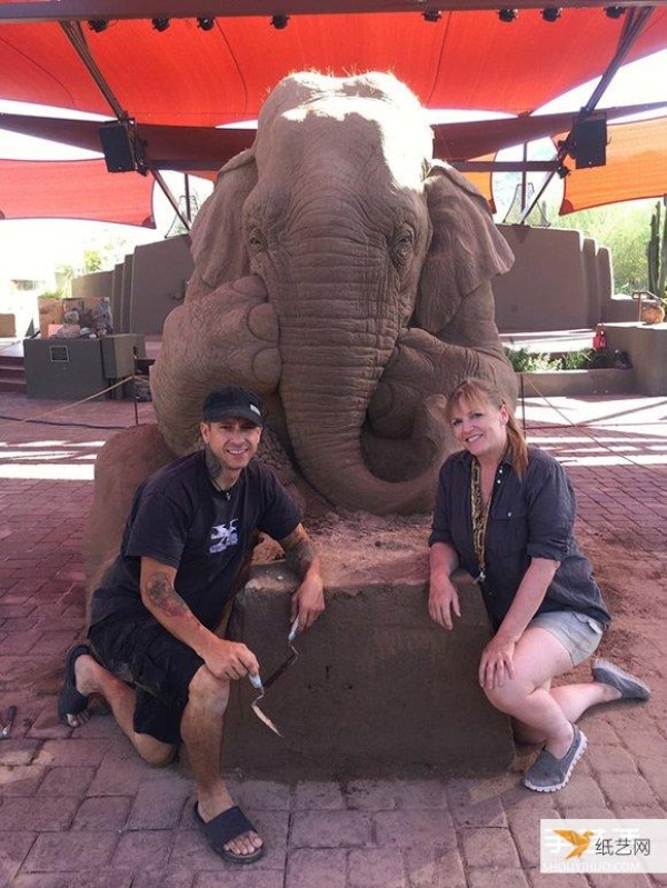 A sand sculpture in the shape of an elephant and mouse playing chess that looks lifelike and full of fairy tale atmosphere