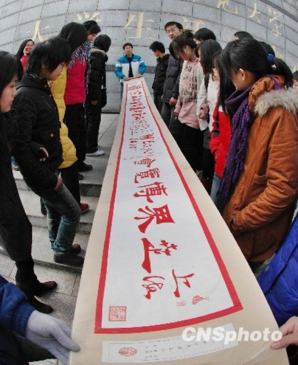 Three college students cut long paper scrolls to bless the Shanghai World Expo