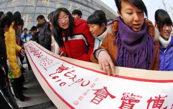 Three college students cut long paper scrolls to bless the Shanghai World Expo