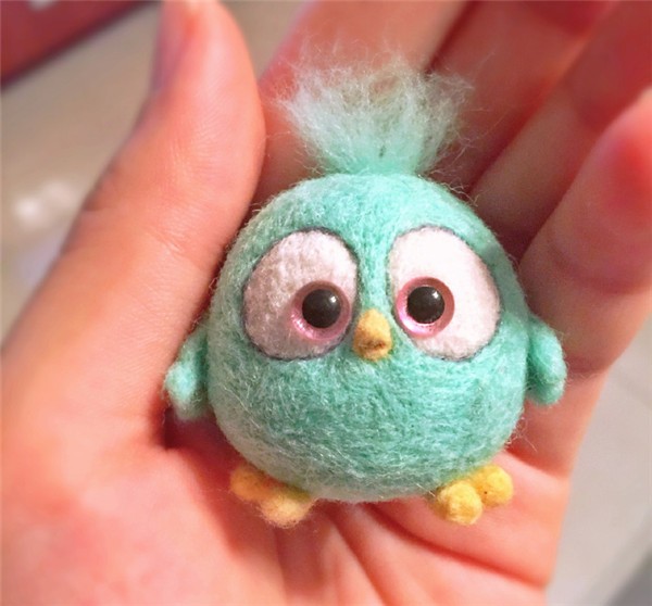 A cute little handmade wool felt DIY bird held in the palm of your hand