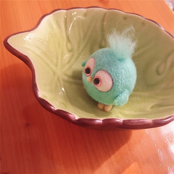 A cute little handmade wool felt DIY bird held in the palm of your hand