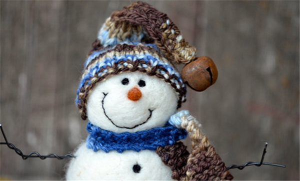 Wool felt handmade creative DIY production of a smiling snowman wearing a hat and scarf