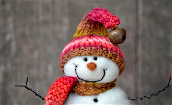 Wool felt handmade creative DIY production of a smiling snowman wearing a hat and scarf