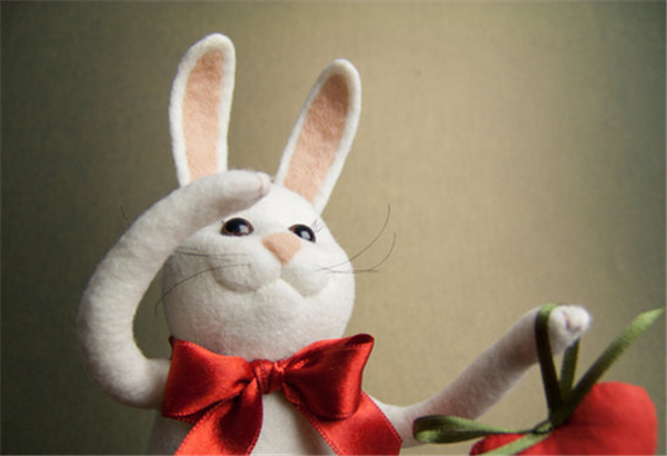 A playful and cute Mr. Rabbit holding a carrot made by DIY using handmade wool felt