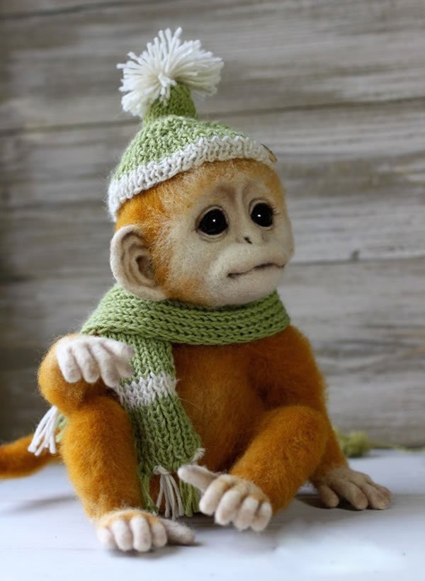 Handmade wool felt playful little monkey wearing a hat and scarf