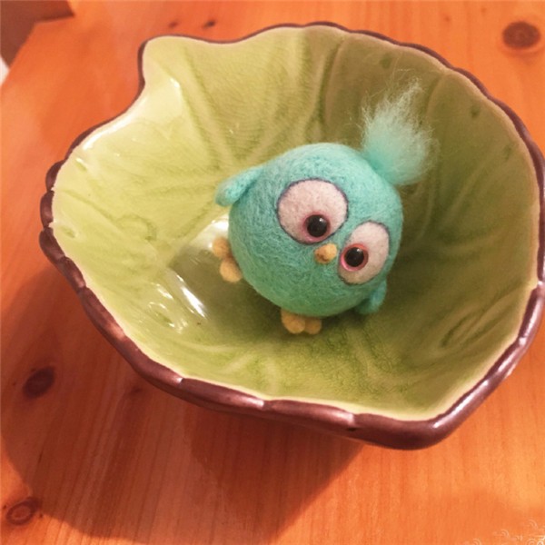 A cute little handmade wool felt DIY bird held in the palm of your hand