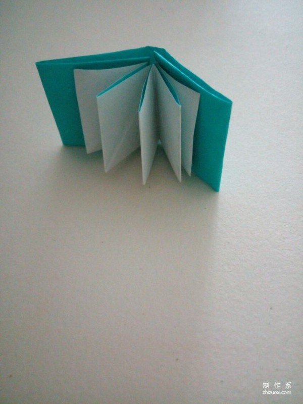 A creative origami real-life tutorial on a mini three-dimensional book-shaped book that can be folded out of just one piece of paper